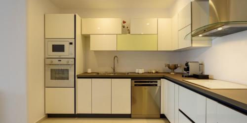a kitchen with white cabinets and stainless steel appliances at Amor Hideaway Villas in Fira