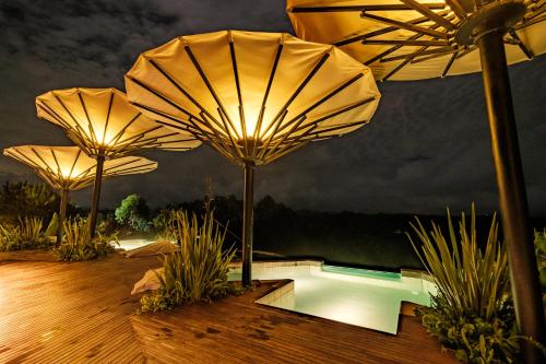 three umbrellas on a deck next to a swimming pool at Bosko in Guatapé