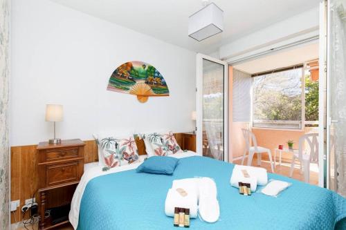 une chambre avec un lit bleu avec des serviettes dessus dans l'établissement Palme d'Or YourHostHelper, à Mandelieu-la-Napoule