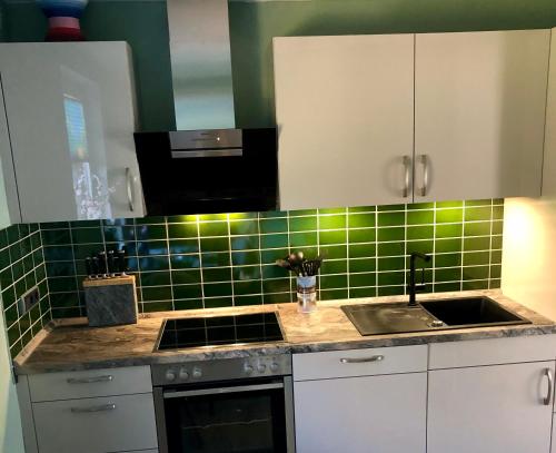 a kitchen with a sink and green tile on the wall at Paradiesje 2 in Leer
