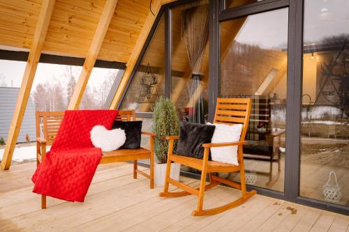 two chairs sitting on a porch with windows at Zenith A-Frame Straja in Lupeni