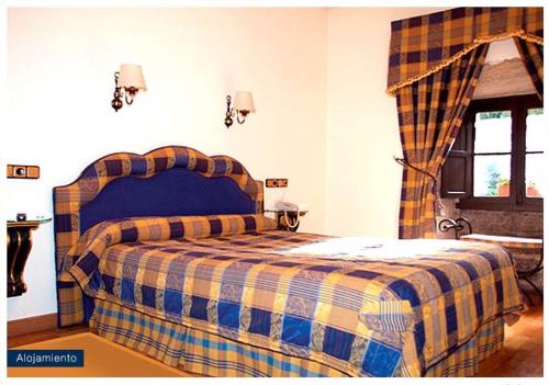 a bedroom with a bed with a checkered blanket at Hospedería Nuestra Sra de las Caldas in Las Caldas de Besaya