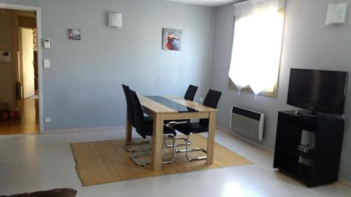 a dining room table with chairs and a television at Meublé de tourisme 2* les Jardins de l Arquebuse in Dijon