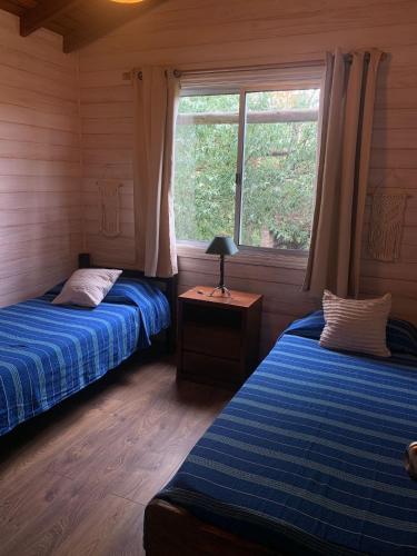 two beds in a room with a window at Cabaña I Punta Negra in Piriápolis