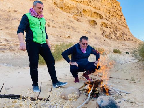 two men standing around a fire in the desert at wadi rum land mars in Wadi Rum