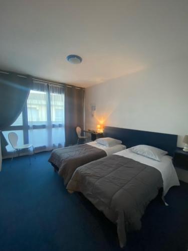 2 camas en una habitación con suelo y ventanas azules en Le Calypso, en Dax