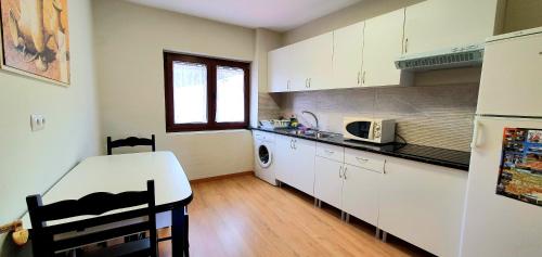 a kitchen with white cabinets and a microwave at Piso El PUNTUAL de arriondas in Arriondas