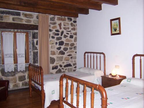 1 dormitorio con 2 camas y pared de piedra en Casa Rural Barbonea, en Lekunberri