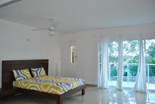 ein Schlafzimmer mit einem Bett und einem großen Fenster in der Unterkunft Vue Apartment Hotel in Cap-Haïtien