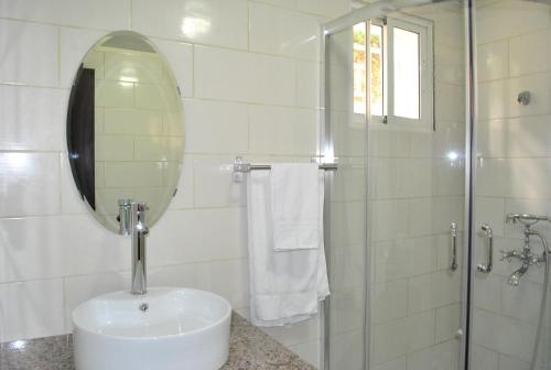 a bathroom with a sink and a shower with a mirror at Vue Apartment Hotel in Cap-Haïtien