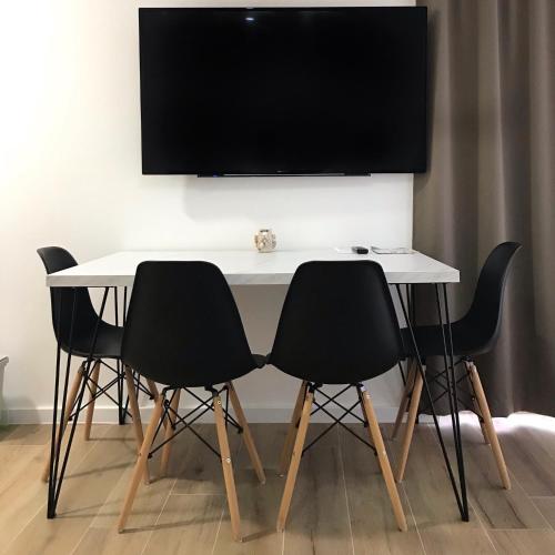 a white table with black chairs and a flat screen tv at Villa Apartment 24 c in Trogir