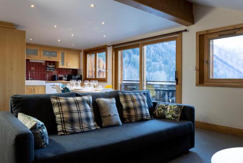 een woonkamer met een blauwe bank en een keuken bij La Snaille des Planards in Chamonix-Mont-Blanc