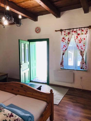 a bedroom with a bed and two windows with curtains at Zulejka Vendégház in Mátraszele