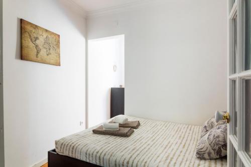 biała sypialnia z łóżkiem z kocem w obiekcie Estrela Garden Apartment w Lizbonie