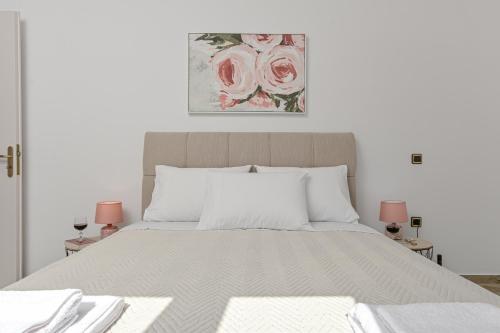 a white bedroom with a large bed with pink lamps at Golden Rose Elegant Vacation Home in Naxos Chora