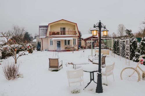 ein Haus mit einem Tisch und Stühlen im Schnee in der Unterkunft Guest House Lorem in Daugavpils