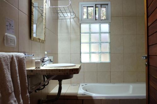 a bathroom with a sink and a tub and a window at Dorado del Sol in Merlo