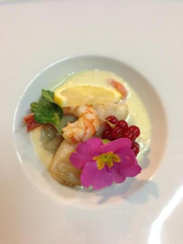 a white bowl of food with fruit and a flower at Logis Hotel La Grange Du Relais in Colombey-les-deux-Églises