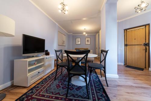 a dining room with a table and chairs and a television at Studio City Center - Victoriei Square in Bucharest