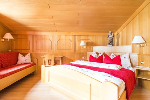 a bedroom with a large bed and a red couch at Chalet Aldian in Selva di Val Gardena