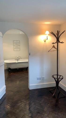 a room with a bath tub and a table and a lamp at Bluebell Barn in Banham