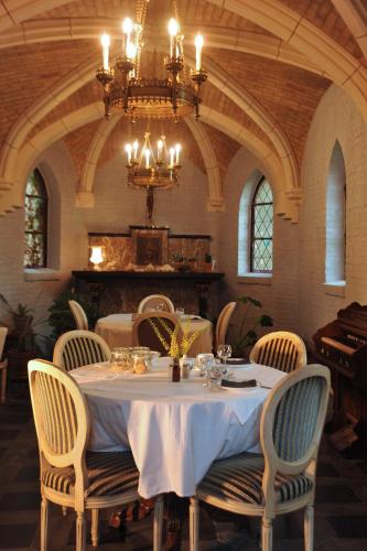 a dining room with a table with chairs and a chandelier at Het Domherenhuis B&B, Restaurant Calice in Heusden - Zolder