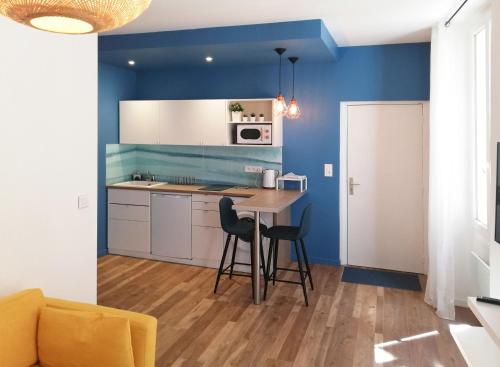 une cuisine avec des murs bleus et une table et des chaises dans l'établissement Appartement de charme centre ville, à La Ciotat