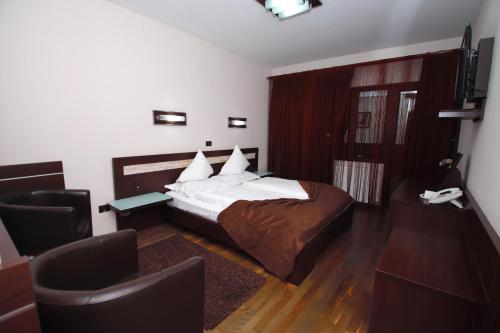 a bedroom with a bed and a desk and a chair at Complex Cochet in Buşteni
