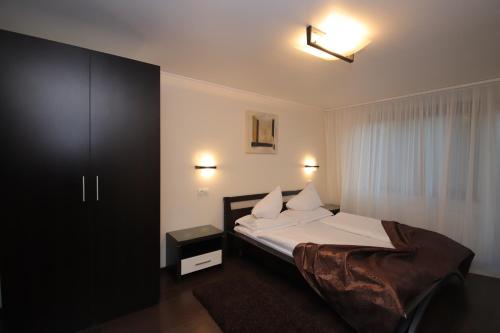 a bedroom with a bed with white sheets and pillows at Complex Cochet in Buşteni