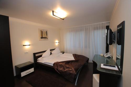 a hotel room with a bed and a desk at Complex Cochet in Buşteni