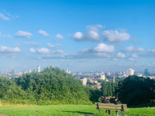 a park bench with a view of a city at Cozy apartment in Hampstead Heath in London