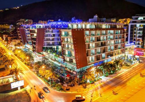 una città illuminata di notte con edifici e palme di Condo Studio Plaza a Budua