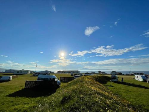 NorthEast Guesthouse في Bakkafjörður: حقل عشبي مع سيارات تقف في حقل