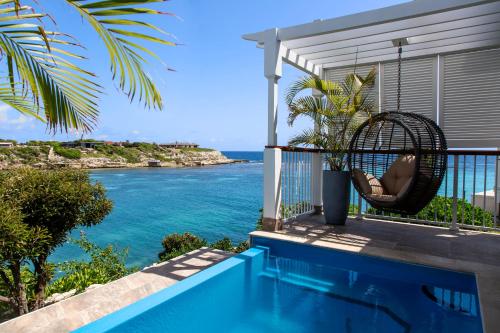 une villa avec une balançoire sur un balcon donnant sur l'océan dans l'établissement Hammock Cove Antigua - All Inclusive - Adults Only, à Willikies