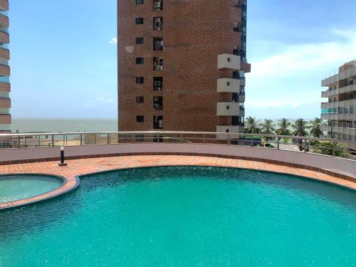 a large swimming pool in front of a tall building at Flat number one temporadalitoranea in São Luís