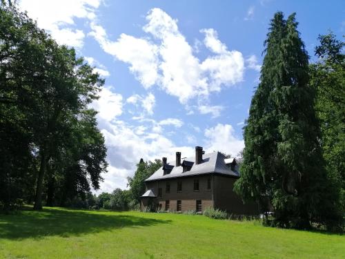 an old house in a field with a tree at Het Domherenhuis B&B, Restaurant Calice in Heusden - Zolder