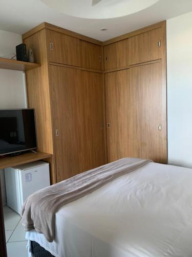 een slaapkamer met een bed, een tv en houten kasten bij Suíte Rio Hotel Residence in Rio de Janeiro