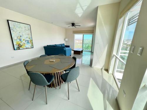 a dining room and living room with a table and chairs at Pacifika 7007 con vista panorámica a la marina in Mazatlán