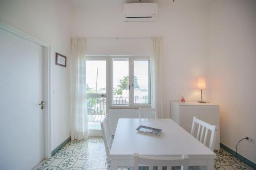 una mesa y sillas blancas en una habitación con ventana en Il Gelso, en Anacapri