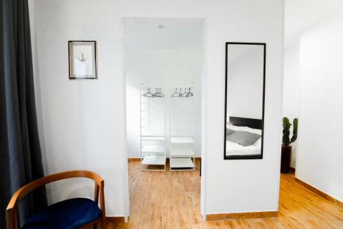 ein weißes Zimmer mit einem Spiegel und einem Stuhl in der Unterkunft Civico64 apartments in Castellammare del Golfo