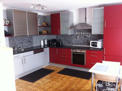 a red kitchen with white cabinets and a microwave at Gästehaus Waldmohr in Waldmohr