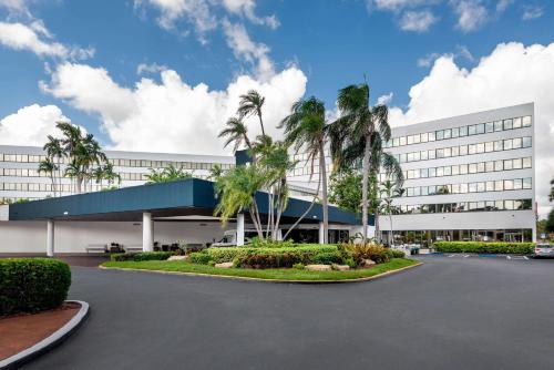 邁阿密的住宿－Sonesta Miami Airport，一座白色的大建筑,前面有棕榈树