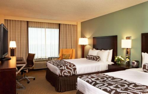 a hotel room with two beds and a television at Sonesta Atlanta Airport North in Atlanta