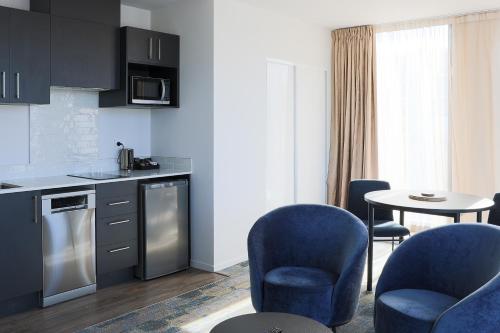 a kitchen with blue chairs and a table at Ramada by Wyndham Wellington Taranaki Street in Wellington