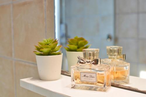 - une étagère dans la salle de bains avec une bouteille de parfum et une plante dans l'établissement Gouvia - Luxury Suite, à Gouviá