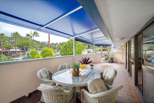 a balcony with a glass table and chairs at Pina Mimosa - Airlie Beach in Airlie Beach