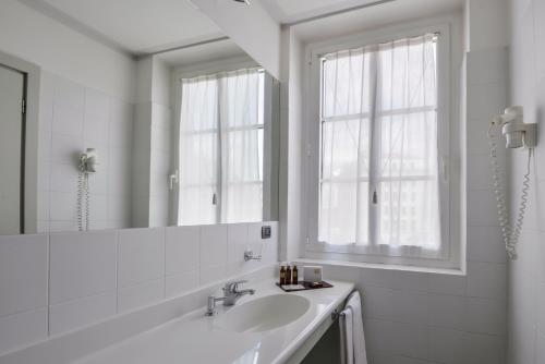W białej łazience znajduje się umywalka i lustro. w obiekcie Albergo Alla Posta w Trieście
