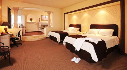a hotel room with two beds and a desk at Hotel & Spa Hacienda Baruk in Zacatecas