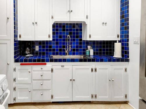 eine Küche mit weißen Schränken und blauen Fliesen in der Unterkunft North Park Bungalow Resort in San Diego