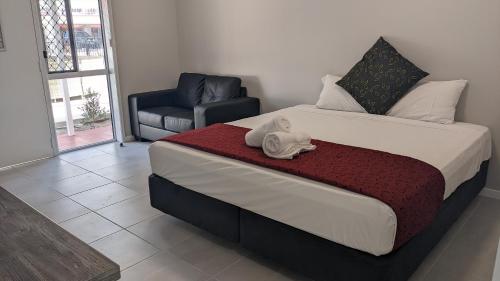 a bedroom with a large bed and a chair at Monte Carlo Motor Inn in Townsville